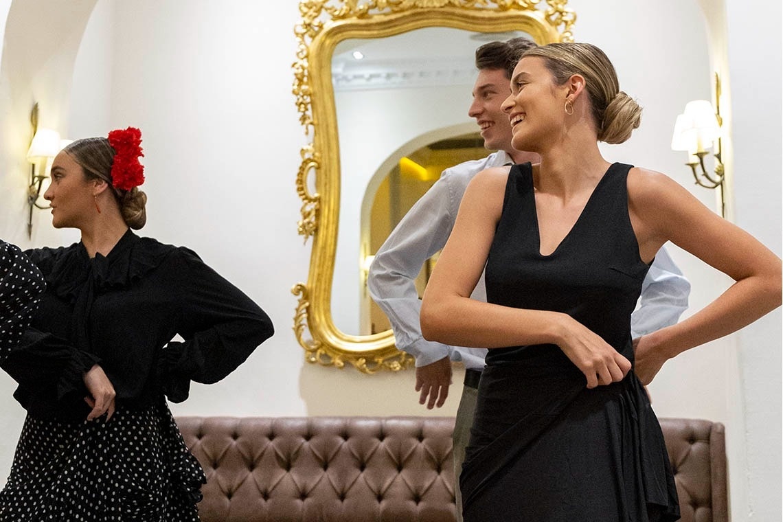 a man and two women are dancing in front of a mirror