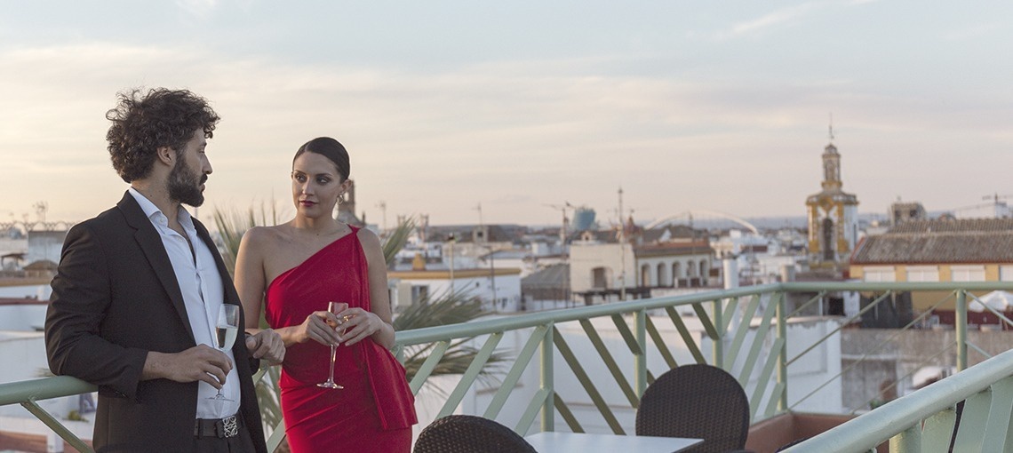 a man and a woman standing on a balcony drinking champagne