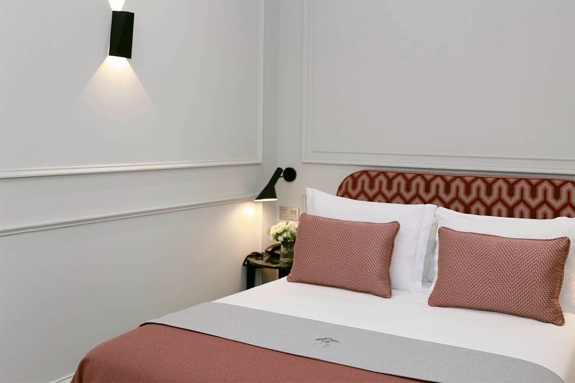 una cama con sábanas blancas y almohadas rosas en una habitación