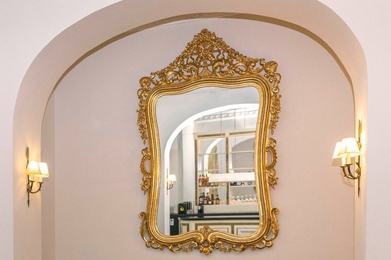 un gran espejo dorado en una pared con dos lámparas
