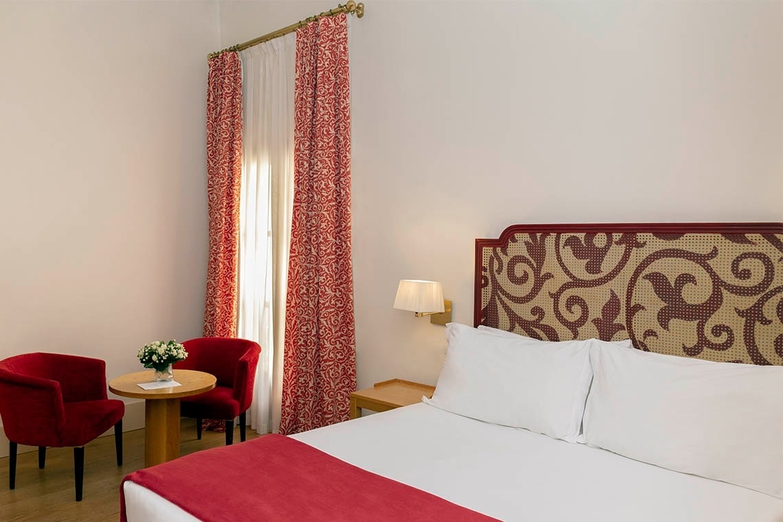una habitación de hotel con una cama y dos sillas rojas