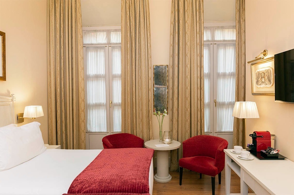 una habitación de hotel con una cama y dos sillas rojas