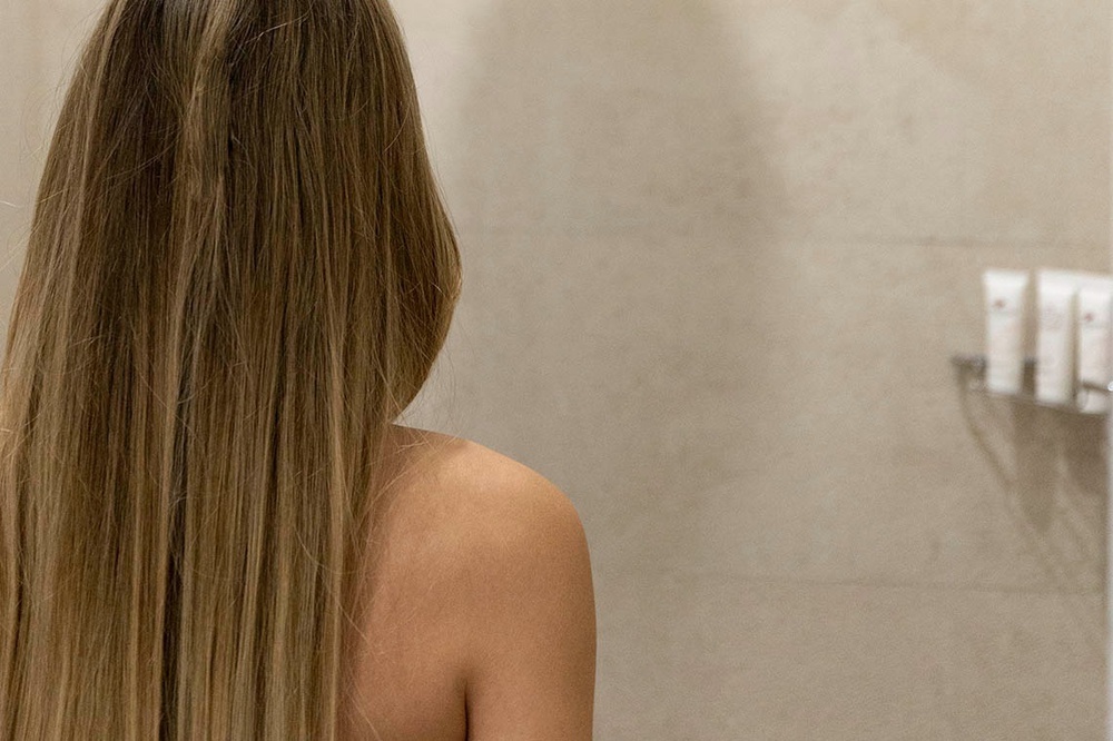 una mujer con cabello largo y recto se mira en el espejo