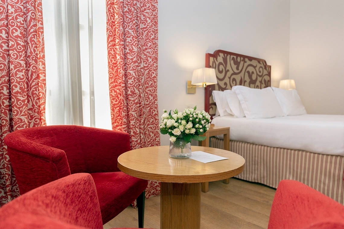 una habitación de hotel con sillas rojas y una mesa redonda