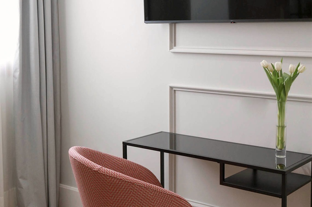 una mesa con un jarrón de tulipanes y un televisor en la pared