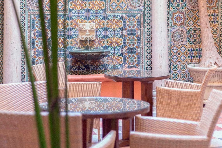 un patio con mesas y sillas y una fuente en la pared