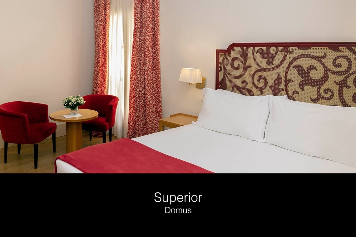 una habitación de hotel con una cama y dos sillas rojas