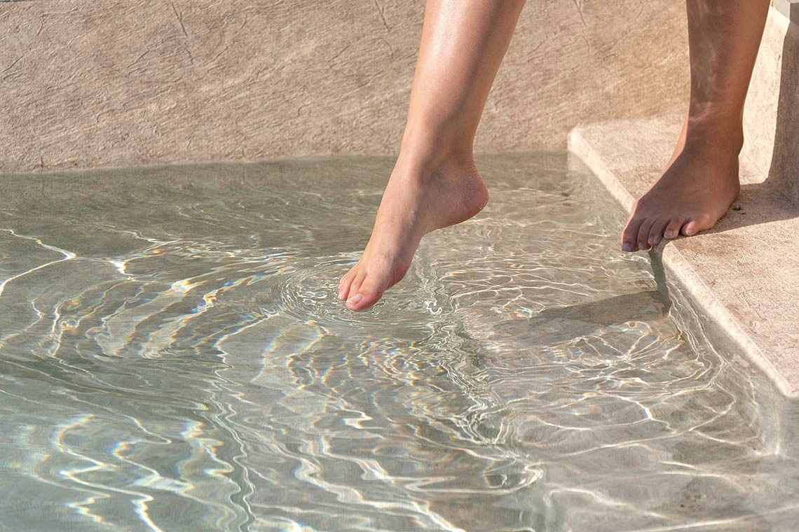 un pie de una persona está en el borde de una piscina