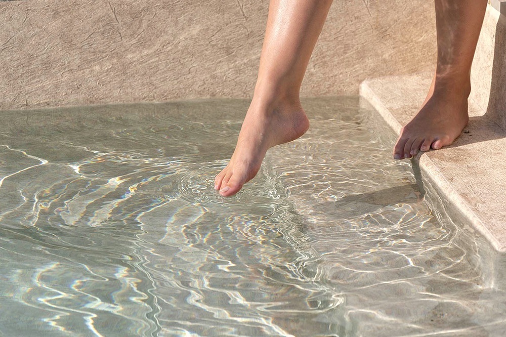 un pie de una persona está en el borde de una piscina