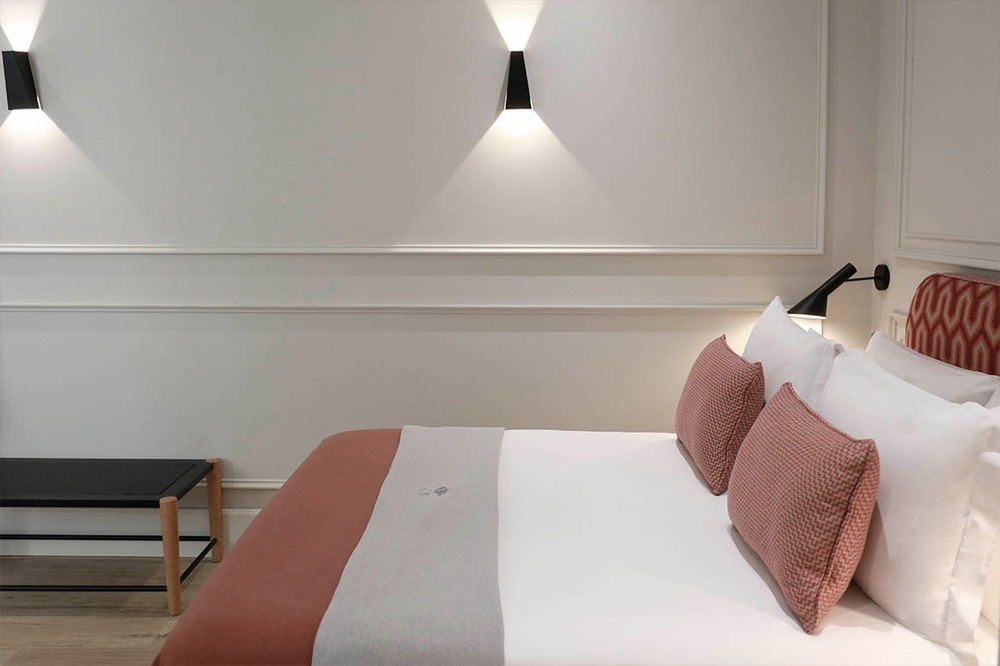 una cama con sábanas blancas y almohadas rojas en una habitación de hotel