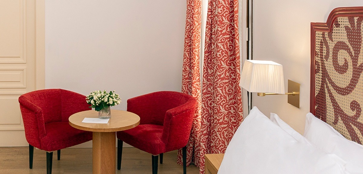 a hotel room with two red chairs and a table
