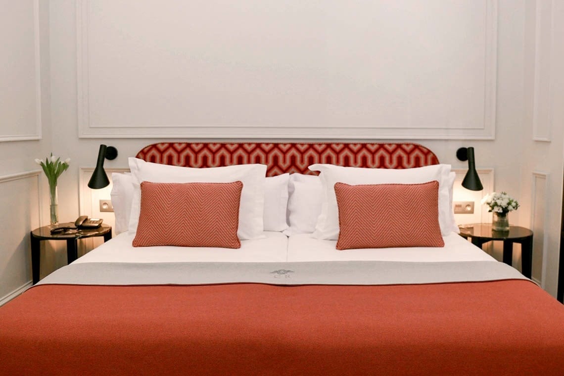 una cama con una manta roja y almohadas rojas en una habitación de hotel