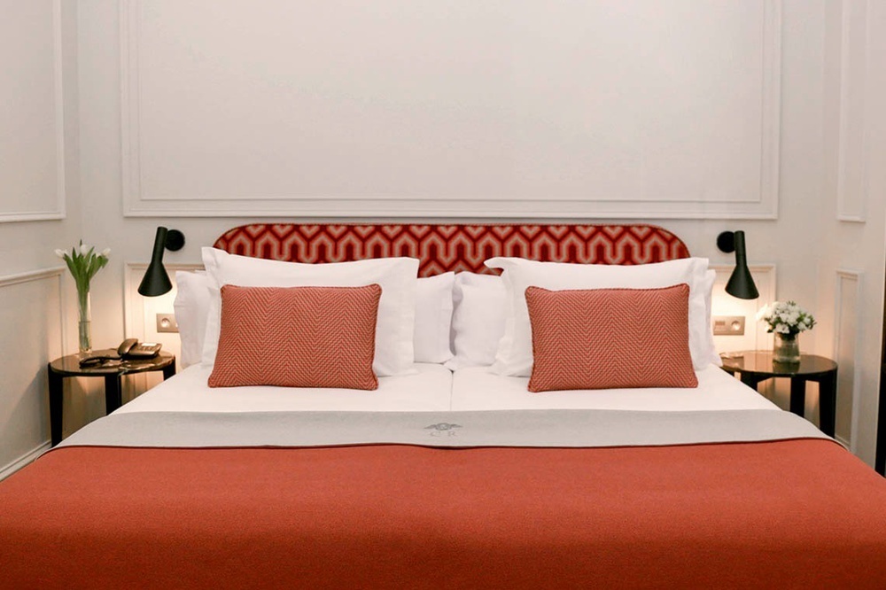 a bed with white sheets and red pillows in a hotel room