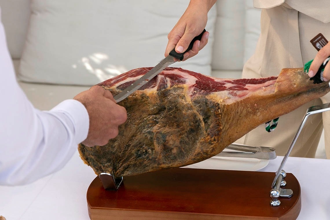 a person is cutting a large piece of meat on a wooden cutting board