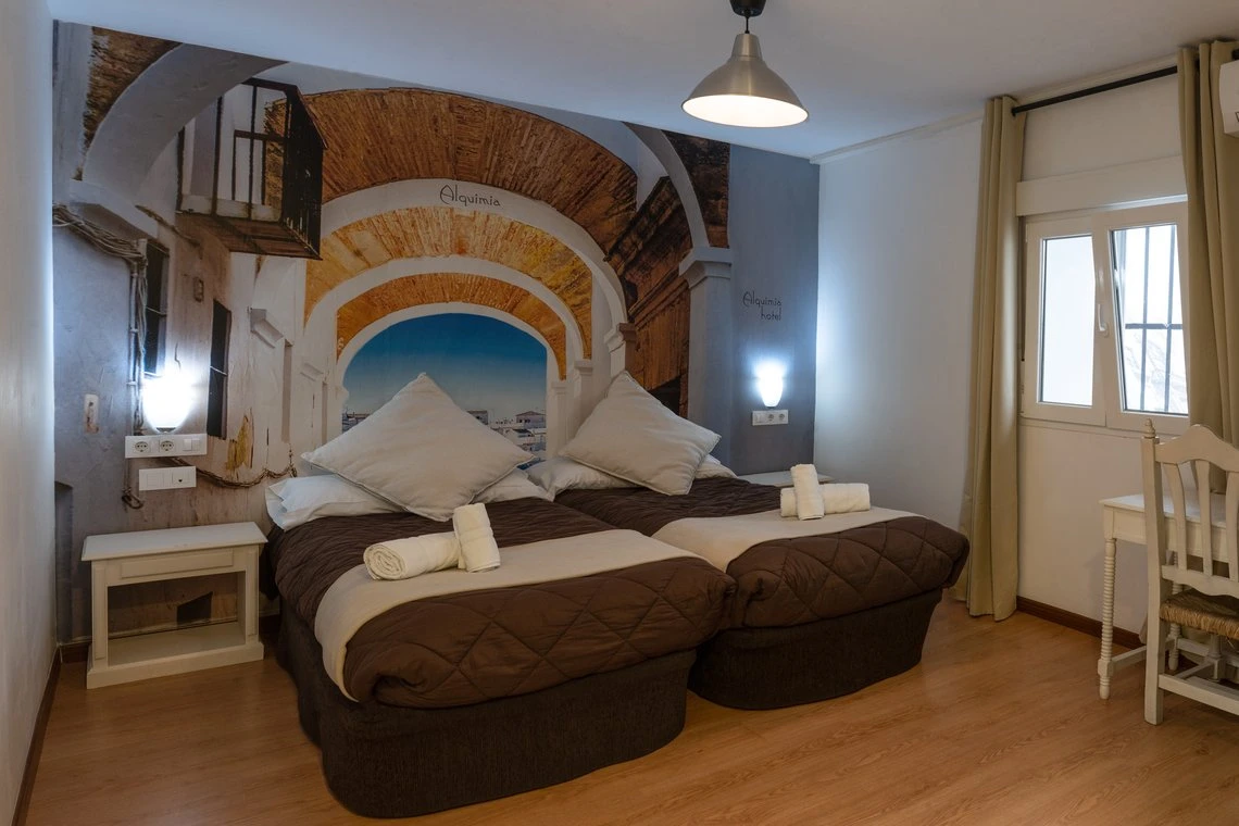 Habitación con dos camas gemelas y mural de Alquimia Casual Alquimia Cádiz.