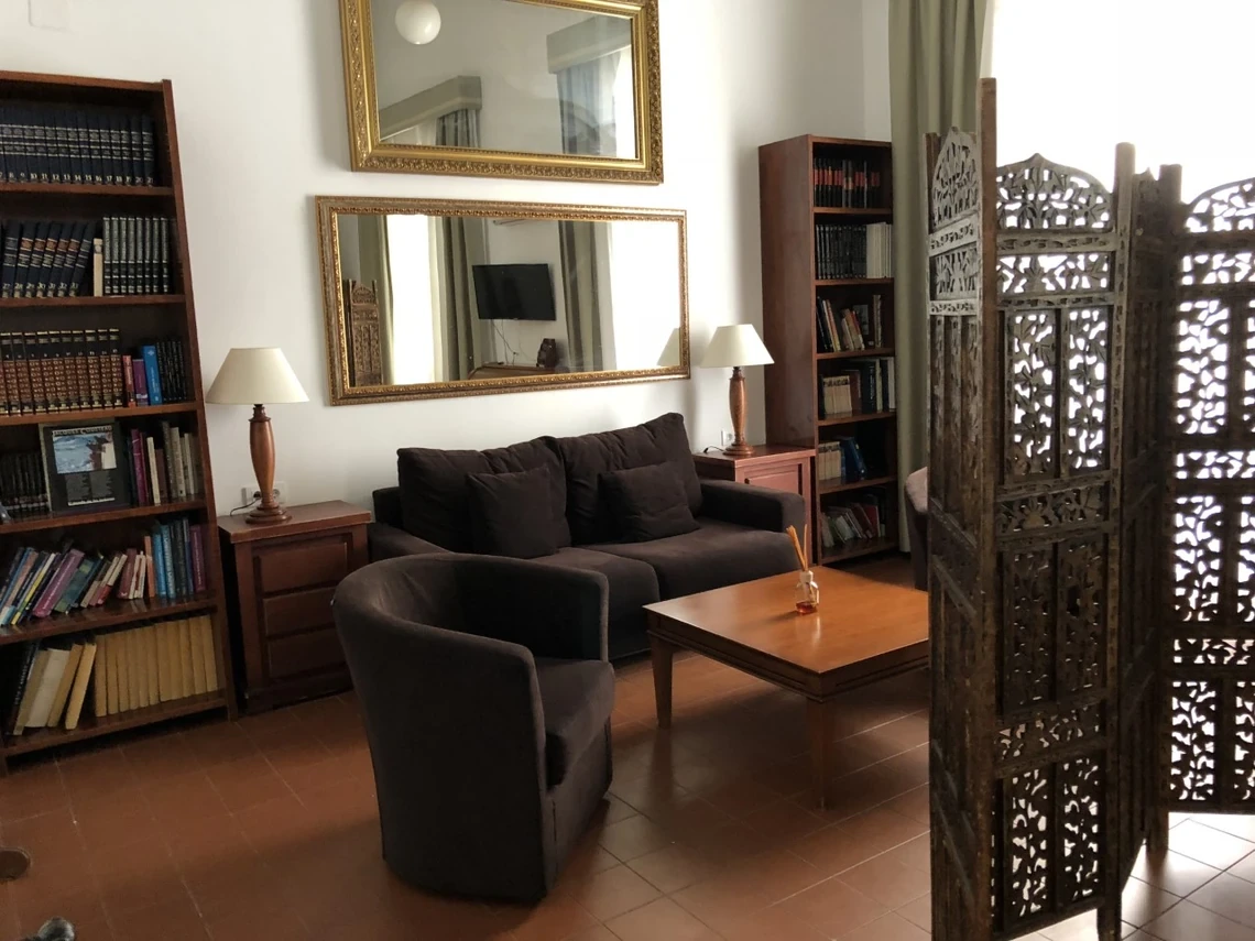 Sala de estar elegante: sofá, sillón, mesa de centro, estanterías y pantalla ornamental. Casual Alquimia Cádiz