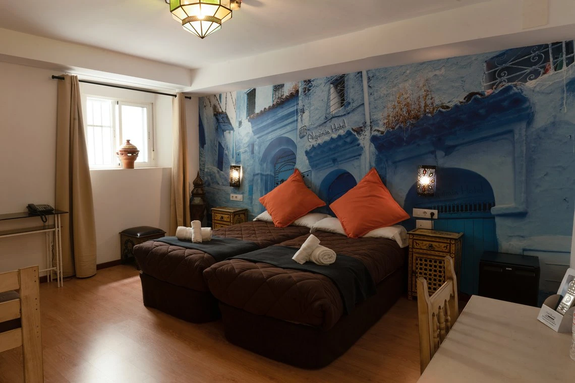 Habitación del Casual Alquimia Cádiz con dos camas, mural azul y decoración marroquí.