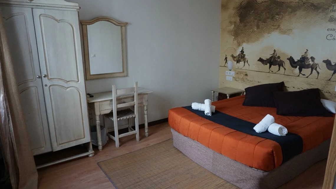 Habitación temática estilo desierto, Casual Alquimia Cádiz con cama naranja, armario y tocador.