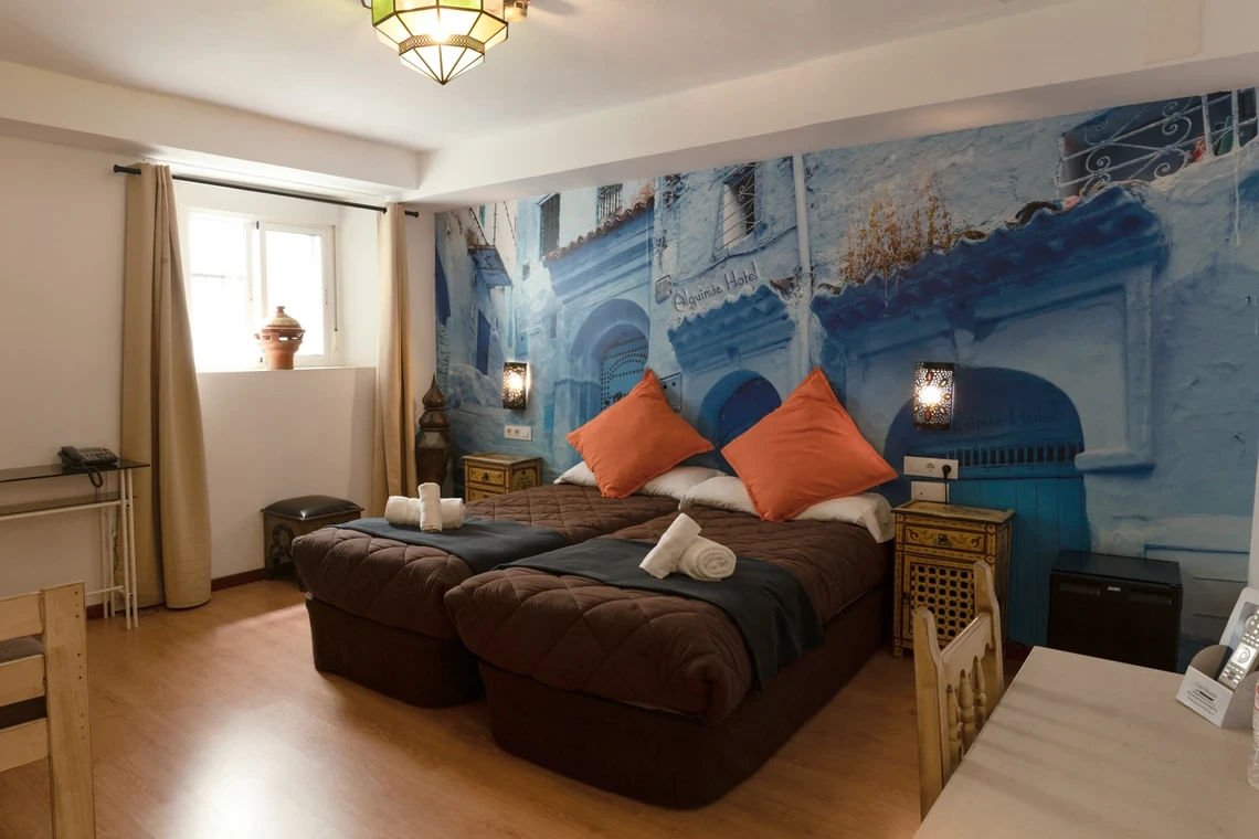 Habitación temática azul en Casual Alquimia Cádiz con dos camas, mural de calle y decoración marroquí.