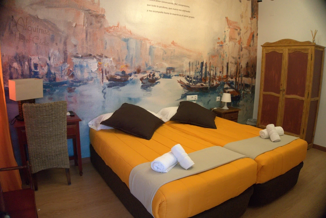 Habitación temática en el Casual Alquimia Cádiz, con mural artístico y cama confortable.