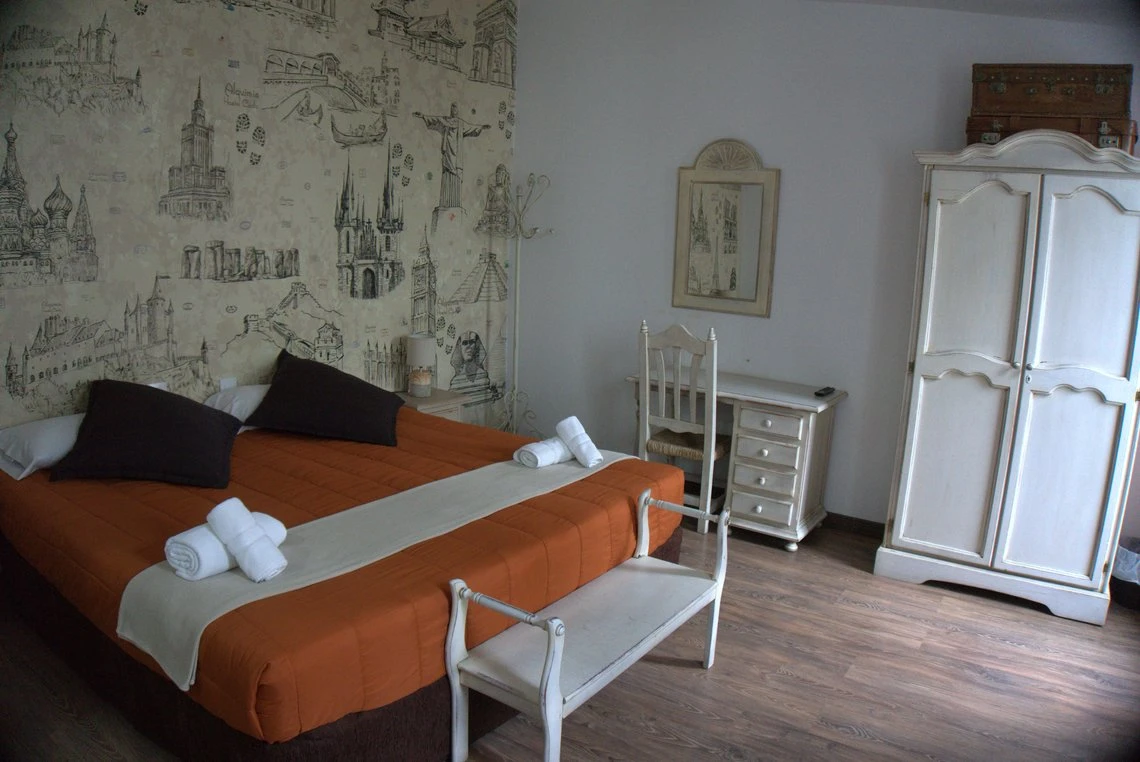 Habitación con cama naranja, armario blanco y espejo. Casual Alquimia Cádiz.