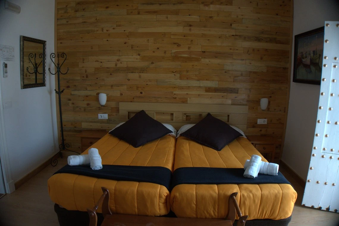 Cama doble acogedora con decoración rústica, ideal para Casual Alquimia Cádiz.