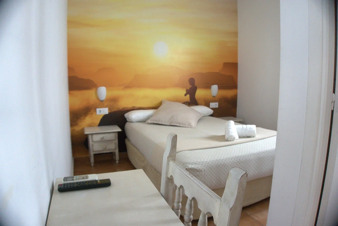 Habitación de hotel con mural de Casual Alquimia Cádiz amanecer y cama cómoda.