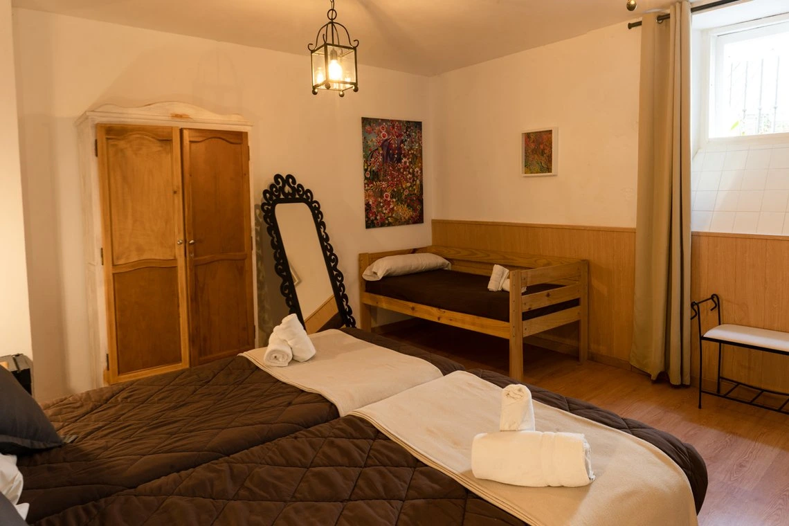 Dormitorio con dos camas, armario antiguo y espejo decorativo. Casual Alquimia Cádiz para familias.