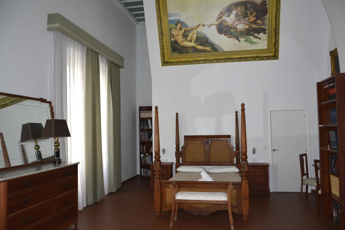 Habitación de hotel clásica con cama con dosel, arte renacentista y biblioteca Casual Alquimia Cádiz.