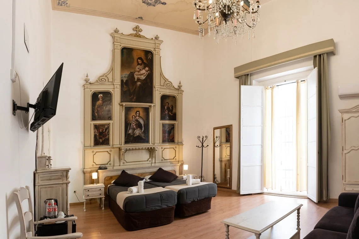 Habitación doble con dos camas, arte religioso y TV plana en hotel Casual Alquimia Cádiz.