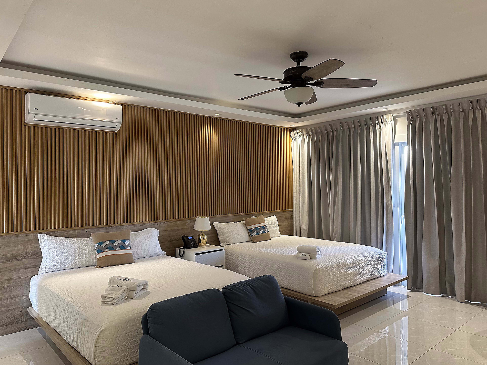 Chambre d'hôtel avec deux lits jumeaux, un canapé et un ventilateur de plafond, idéale pour Casual: On The Beach Bayahibe.