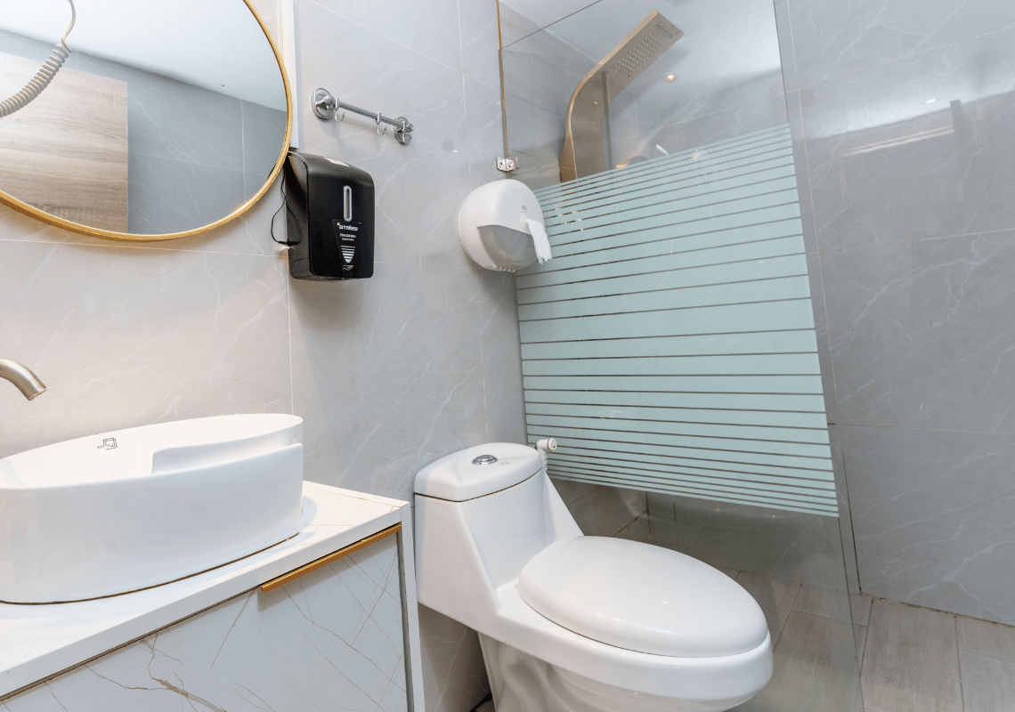 Baño moderno con lavabo, inodoro y ducha de vidrio Casual: On The Beach Bayahibe.