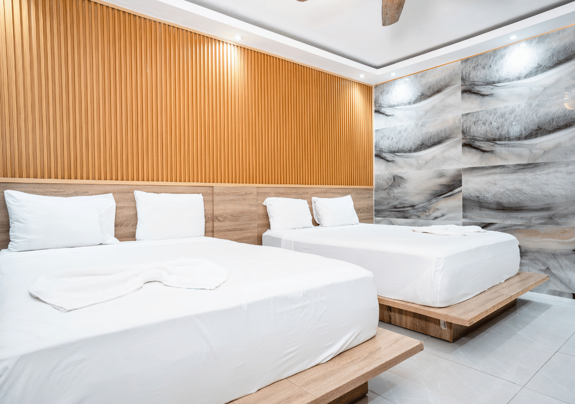 Habitación con dos camas dobles, pared de listones de madera y papel tapiz de mármol, ideal para Casual: On The Beach Bayahibe.