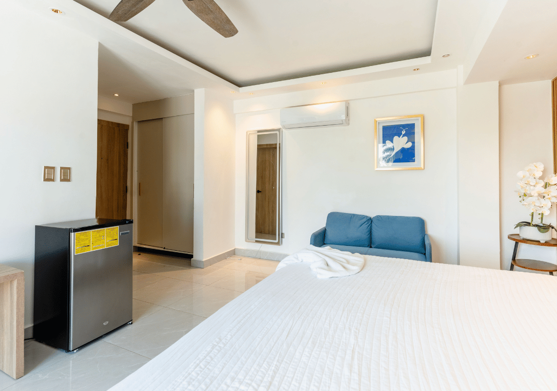 Suite moderna con cama grande, sofá azul, Casual: On The Beach Bayahibe y mini-nevera.