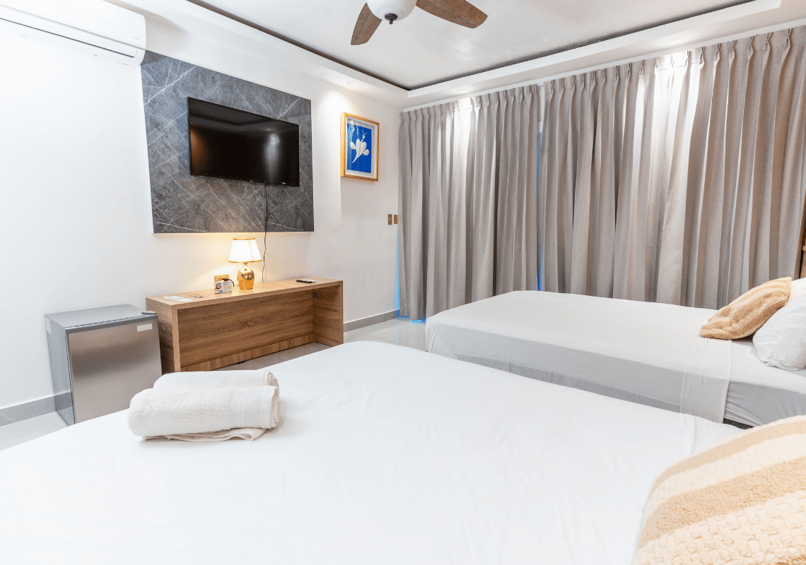 Habitación con dos camas gemelas, TV, mini-nevera y cortinas: Casual: On The Beach Bayahibe ideal.