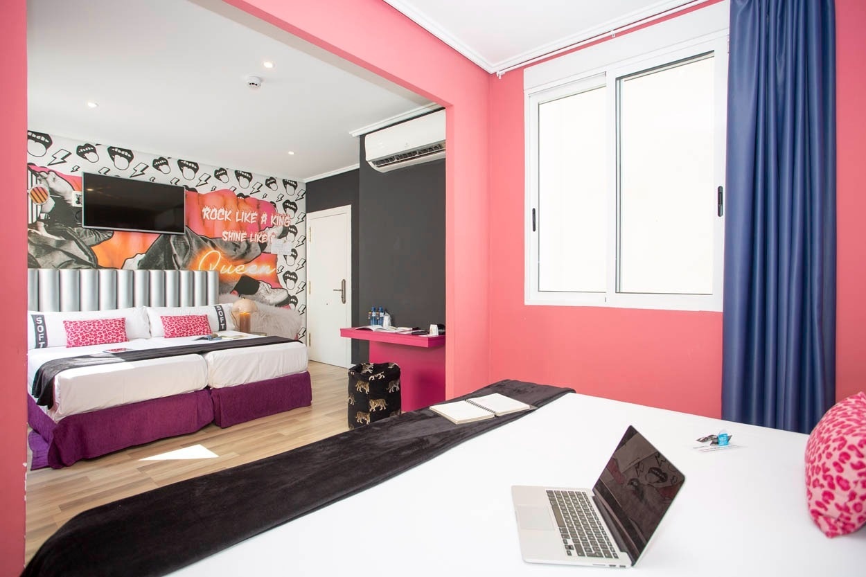 Habitación moderna y chic en Casual Vintage Valencia: camas gemelas, mural llamativo y escritorio rosa.