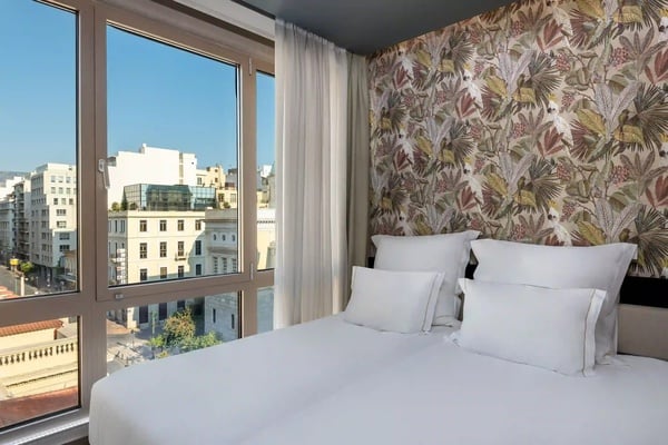 een hotelkamer met een bed en een groot raam