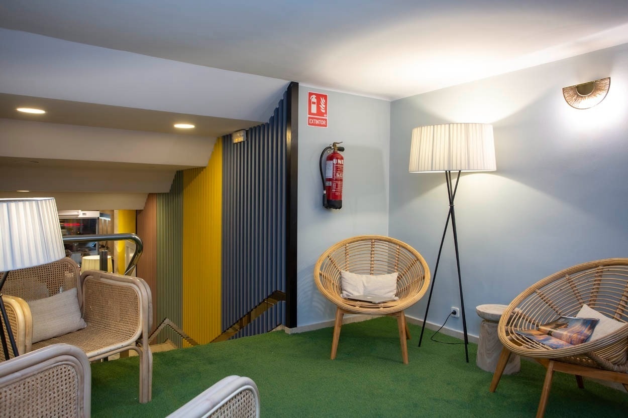 Ontspannen zithoek met rieten stoelen en een staande lamp bij Casual Colours Barcelona - Hotel nabij Sants.
