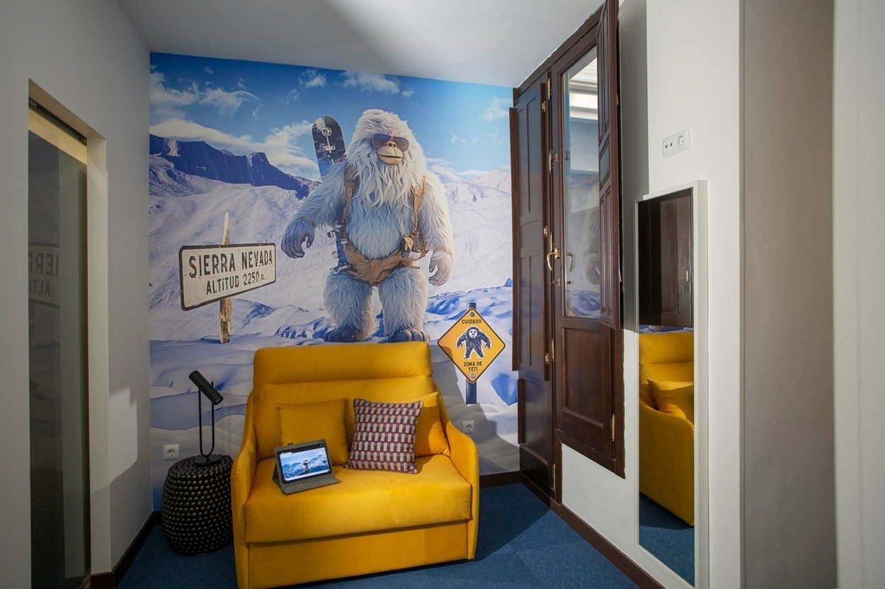 Casual Ilbira Granada: Divertido rincón con mural de Yeti y sofá amarillo.