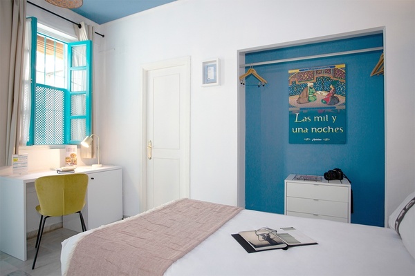 una habitación con una cama y un escritorio y un cartel que dice las mil y una noches