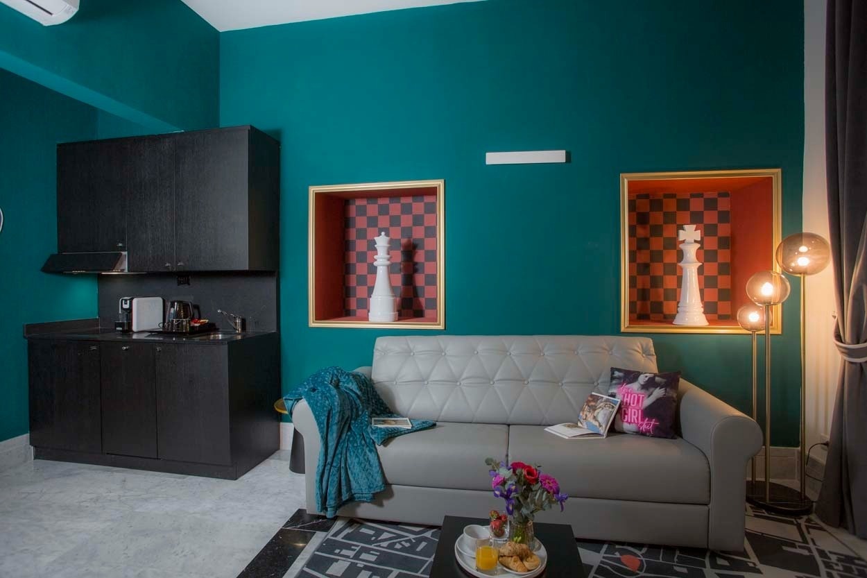 Ein stilvolles Wohnzimmer in Casual Rinascimento Firenze mit tealfarbenen Wänden, zwei Schachfiguren und einem bequemen Sofa.