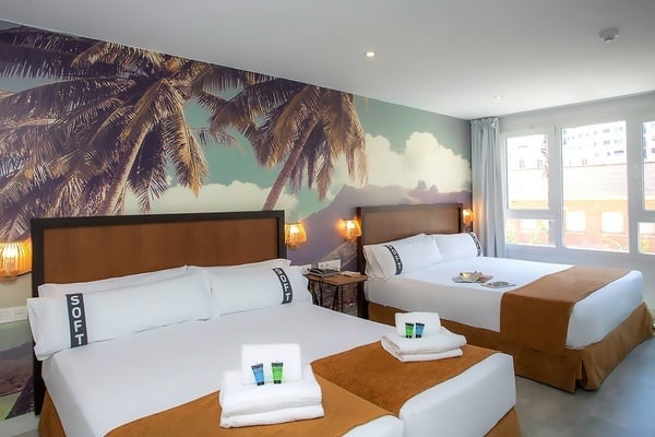 una habitación de hotel con dos camas y un mural de palmeras en la pared
