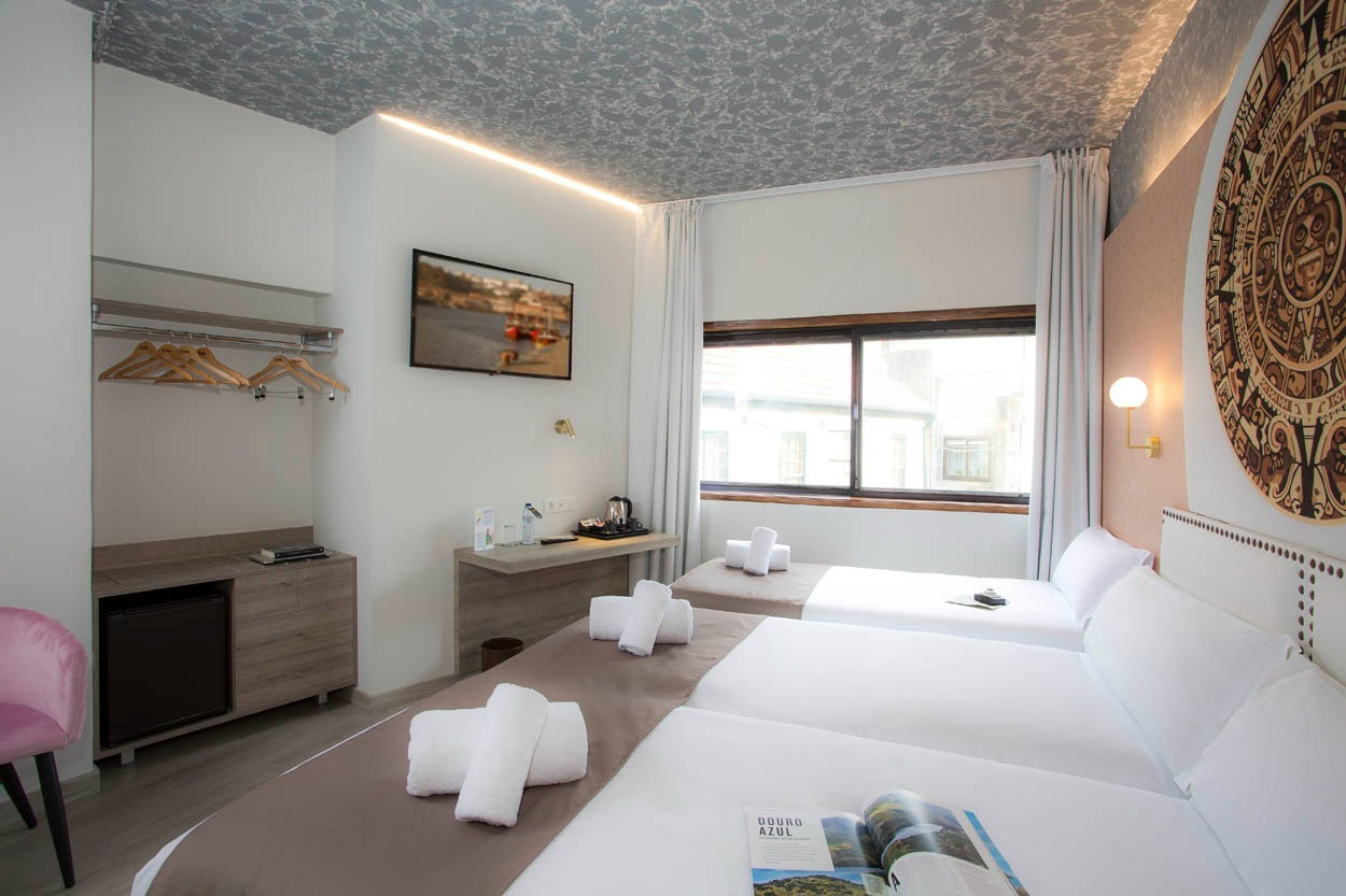 Gemütliches Hotelzimmer mit drei Betten, ideal für Familien oder Gruppen im Casual Inca Porto.