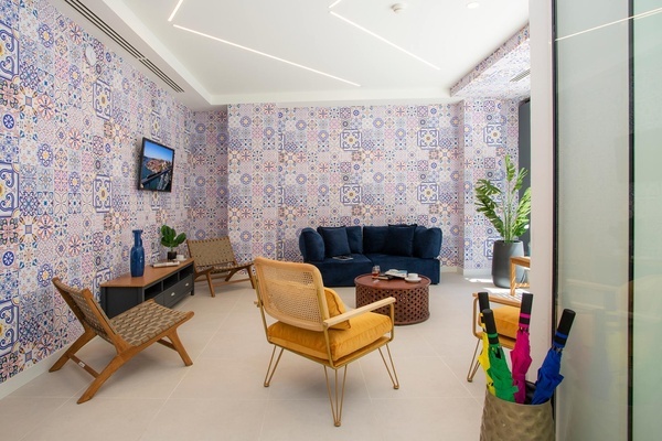 a living room with a couch and chairs and a tv on the wall