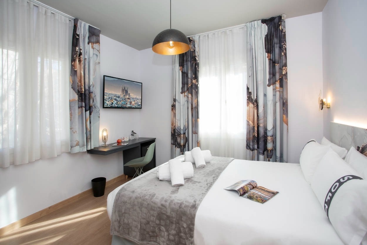 Moderne hotelkamer met stijlvolle gordijnen en uitzicht op de stad, ideaal voor een verblijf in Casual Colours Barcelona - Casual Hoteles.