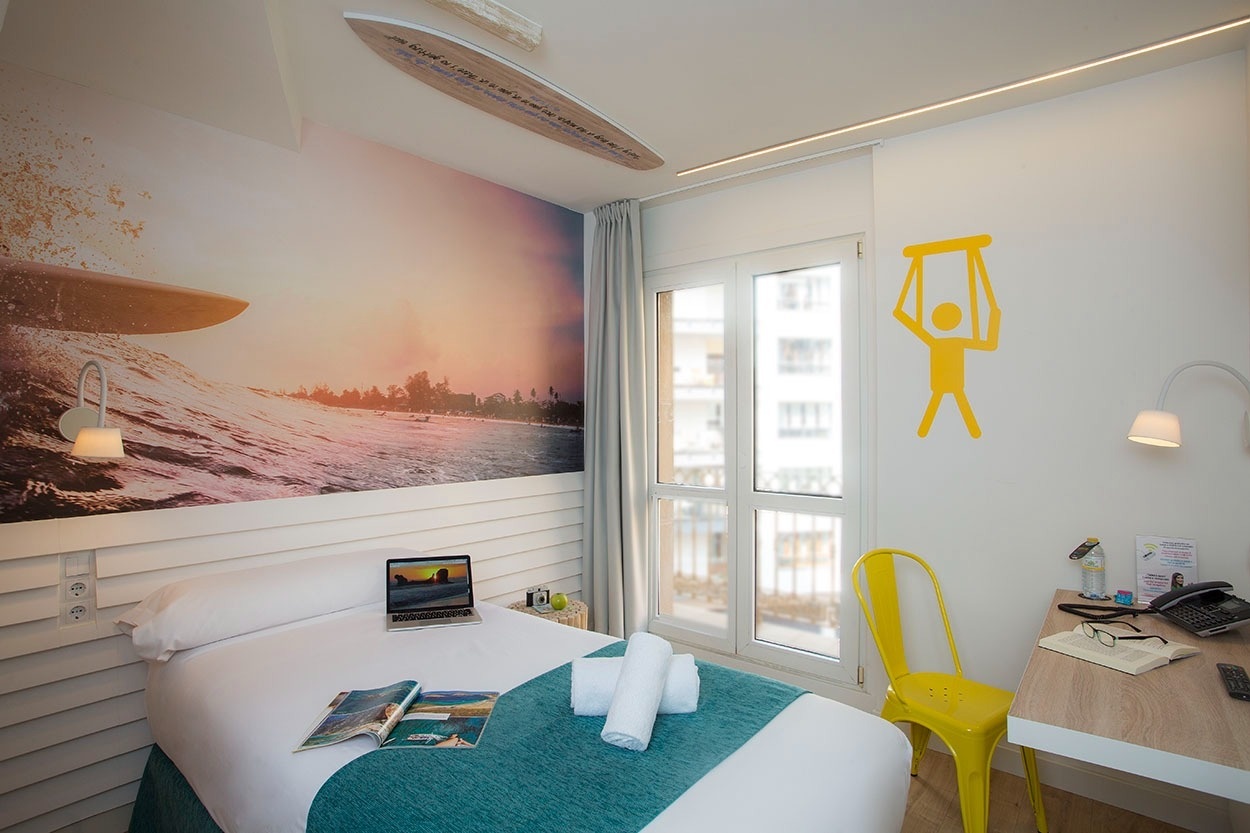 Casual de las Olas San Sebastián - Themenhotel mit Surfer-Wandbild und gelbem Stuhl
