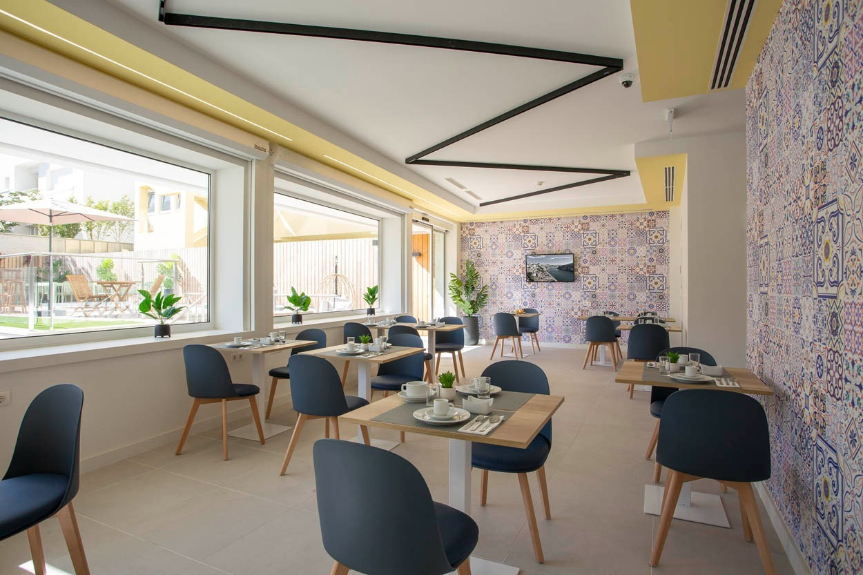 Sala colazioni luminosa con tavoli apparecchiati, ideale per un soggiorno Casual Raízes Porto - Boutique hotel.