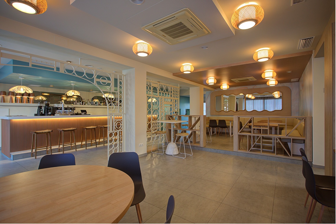Café lumineux style Casual Corporate avec tables en bois et sièges sombres.