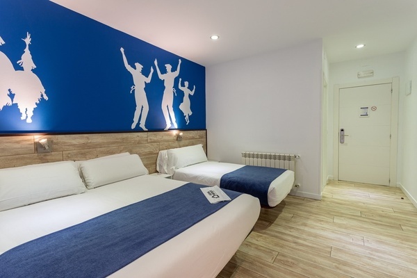 a hotel room with two beds and a blue wall