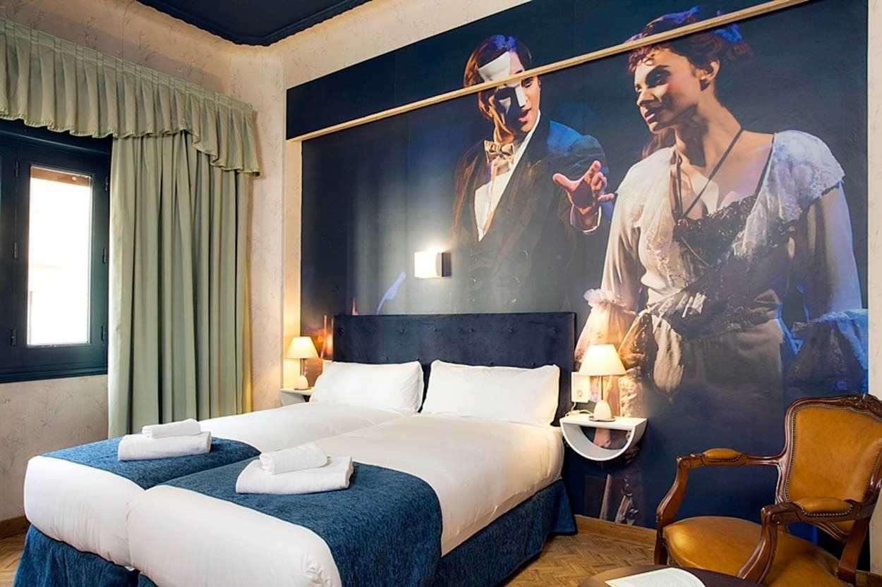 Gemütliches Schlafzimmer im Casual del Teatro Madrid mit Wandgemälde im Theaterstil, nahe der Gran Vía.